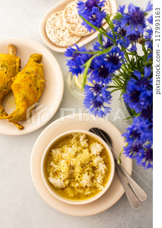 Stewed rabbit with rice, broccoli and rice cakes, a served table with food and a vase of flowers Stewed rabbit with rice, broccoli and rice cakes, a served table with food and a vase of flowers 117993163