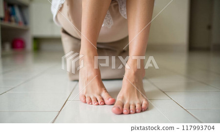 Elegant bare female feet on wooden floor, graceful ankles, soft skin, pedicure beauty, natural pose indoors, feminine foot care wellness 117993704