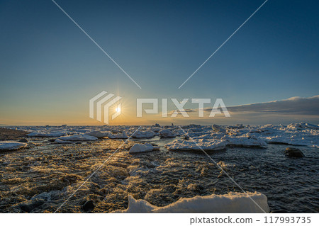 Drift ice illuminated by the setting sun washes over the coast of Shiretoko 117993735