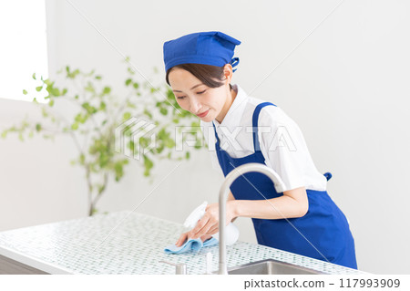 A woman from a housekeeping service cleaning the kitchen A woman from a housekeeping service cleaning the kitchen 117993909