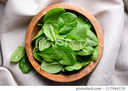 Baby spinach leaves with water drops in a wooden bowl 117994229