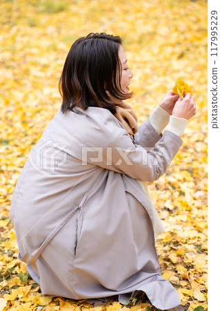 Young woman enjoying autumn leaves hunting Young woman enjoying autumn leaves hunting 117995229