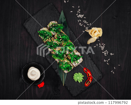 Delicious sushi rolls with algae and sesame seeds on black stone background Delicious sushi rolls with algae and sesame seeds on black stone background 117996792