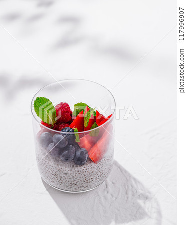 Chia seed pudding decorated with fresh berries and mint leaves on white background 117996907