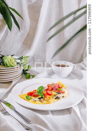 Delicious omelette with tomatoes, mushrooms, basil and ham for breakfast 117996909
