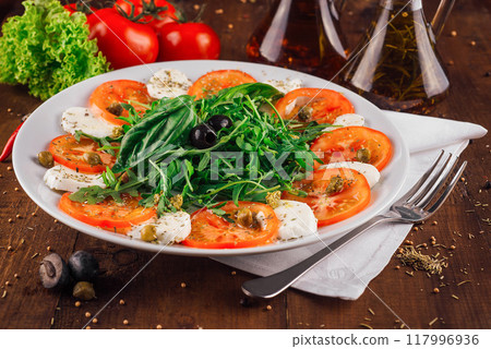 Caprese salad with tomatoes mozzarella and basil on wooden table Caprese salad with tomatoes mozzarella and basil on wooden table 117996936