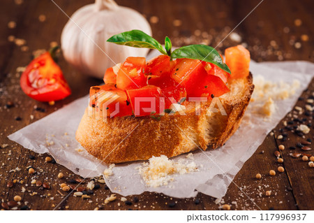 Delicious bruschetta with tomatoes and basil sitting on wooden table Delicious bruschetta with tomatoes and basil sitting on wooden table 117996937