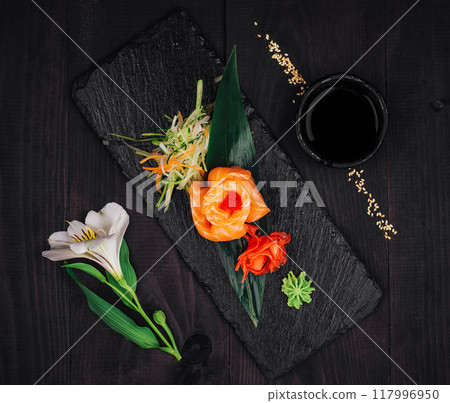 Salmon sashimi rose served on slate with wasabi and ginger on dark wooden table 117996950
