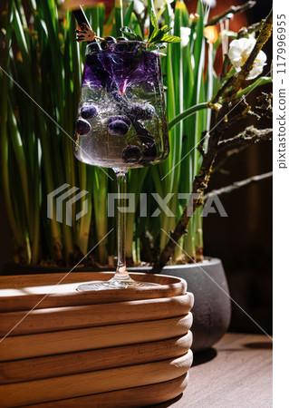 Sparkling cocktail with blueberries and mint standing on wooden tray Sparkling cocktail with blueberries and mint standing on wooden tray 117996955