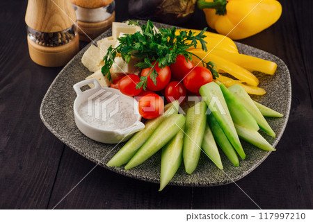Plate presenting sliced cucumbers, tomatoes, cheese and peppers with spices aside Plate presenting sliced cucumbers, tomatoes, cheese and peppers with spices aside 117997210