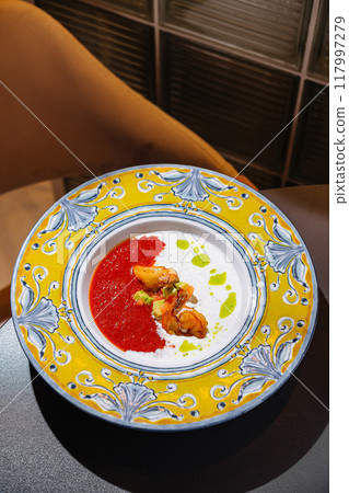 Delicious soup with shrimps served in a beautiful plate in a restaurant Delicious soup with shrimps served in a beautiful plate in a restaurant 117997279