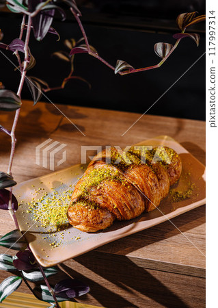 Freshly baked croissant decorated with pistachios lying on plate Freshly baked croissant decorated with pistachios lying on plate 117997314