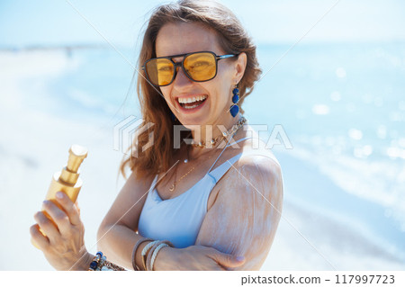 smiling elegant woman on seashore with sunscreen smiling elegant woman on seashore with sunscreen 117997723