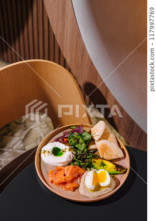 Healthy breakfast plate combining smoked salmon, poached egg and avocado 117997769