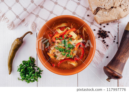 Bowl of chicken soup with vegetables on white table being prepared for eating 117997776