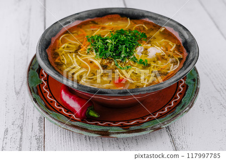 Chicken soup with noodles and vegetables served on white table background 117997785