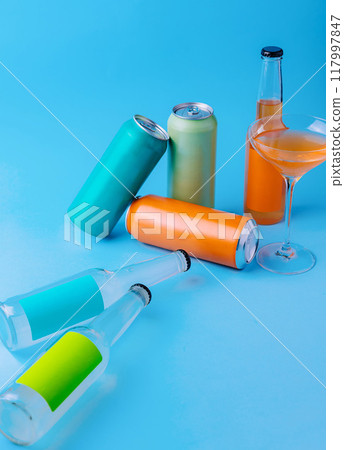 Colorful aluminum cans and glass bottles lying on blue background Colorful aluminum cans and glass bottles lying on blue background 117997847