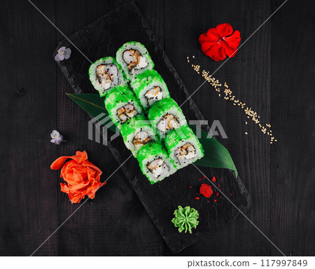 Green dragon sushi rolls with eel and avocado lying on black slate plate Green dragon sushi rolls with eel and avocado lying on black slate plate 117997849