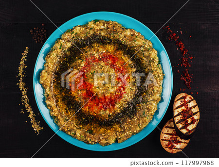 Baba ghanoush decorated with olive oil and spices lying on a blue plate Baba ghanoush decorated with olive oil and spices lying on a blue plate 117997968