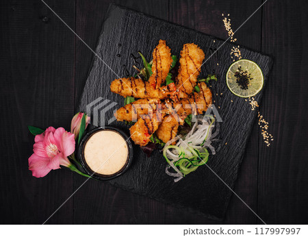 Delicious fried shrimps being served on black stone with vegetables and sauce Delicious fried shrimps being served on black stone with vegetables and sauce 117997997