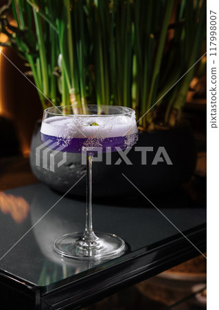 Purple cocktail with egg white foam standing on table 117998007