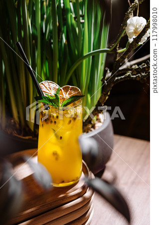 Refreshing passion fruit lemonade with ice and mint on wooden table 117998010