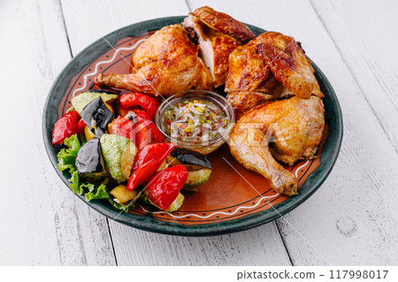 Roasted chicken with vegetables and sauce on rustic plate 117998017