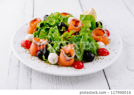 Delicious salad with smoked salmon, mozzarella and cherry tomatoes on white table 117998018