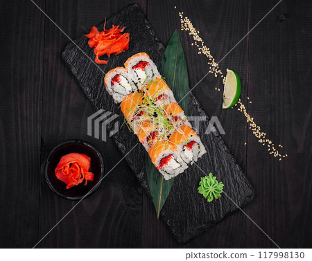 Sushi rolls set served on black stone slate on dark wooden table 117998130