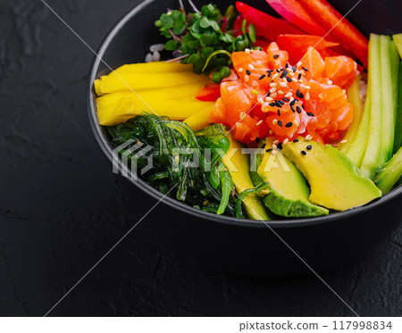 Fresh salmon poke bowl on dark background 117998834