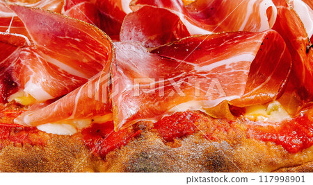 Delicious prosciutto topped pizza close up Delicious prosciutto topped pizza close up 117998901