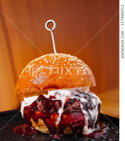 Gourmet burger with creamy sauce on black plate 117998912
