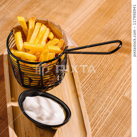 Golden french fries in a serving basket with dip 117998941