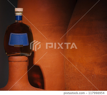 Artistic display of cognac bottle on clay sculpture 117998954