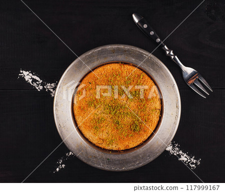 Traditional turkish dessert kunefe knefe serving on dark rustic table 117999167