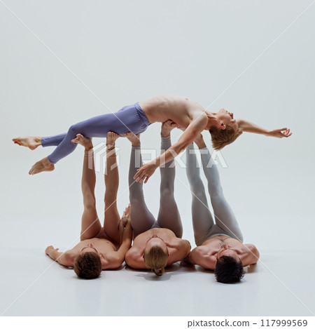 Dancers support lifted performer with precision, their coordinated movements creating seamless and elegant lift against white studio background. Dancers support lifted performer with precision, their coordinated movements creating seamless and elegant lift against white studio background. 117999569