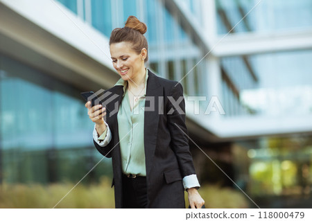happy woman worker near office building using phone and walking 118000479