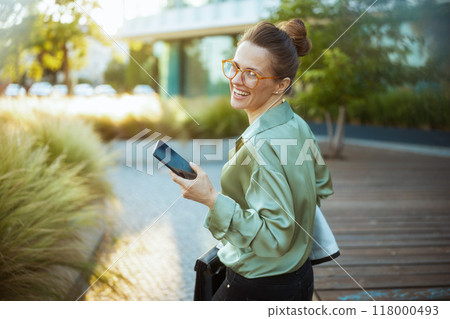 woman employee in green blouse using phone and walking 118000493
