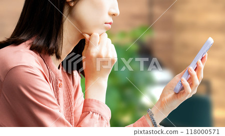 Young business woman looking at smartphone and thinking Young business woman looking at smartphone and thinking 118000571