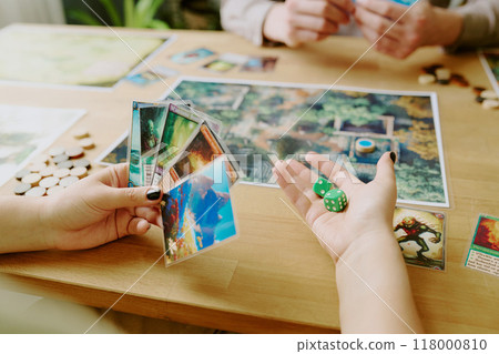 Unrecognizable fantasy board game player holding colorful cards and green dice in hands 118000810