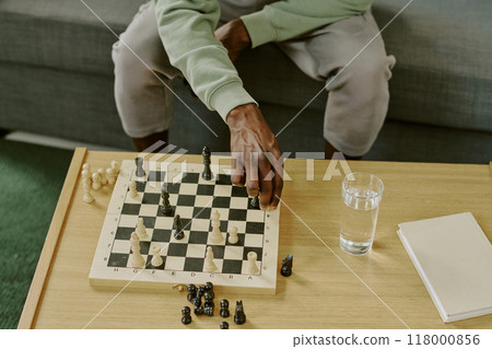 High angle view of hand of unrecognizable Black man moving chess piece while solving problem 118000856