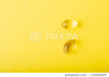 Vitamin C, omega 3 fish oil close up. Supplement soft capsule isolated on yellow background. Cod liver oil closeup. Vitamins in soft capsule. Healthcare concept. Copy space, banner. High quality photo 118000994