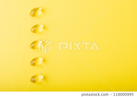 Omega 3 fish oil, vitamin C top wiev. Supplement soft capsule isolated on yellow background. Cod liver oil close up. Vitamins soft capsule. Healthcare concept. Copy space, banner. High quality photo 118000995