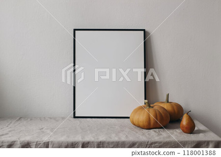 Autumn still life. Vertical thin black picture frame mockup. Orange pumpkins, pear fruit on linen table cloth. White wall background. Minimal rustic interior, neutral color. Halloween, Thanksgiving 118001388
