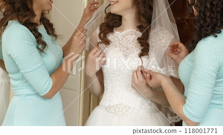 Bride friends are helping to dress her 118001771