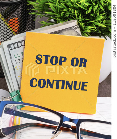 STOP OR CONTINUE written on a yellow sticker, vertical concept photo STOP OR CONTINUE written on a yellow sticker, vertical concept photo 118001804