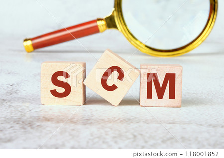 SCM short for Supply Chain Management. SCM on wooden cubes with a magnifying glass in the background 118001852