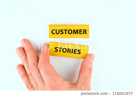Business concept. Customer Stories words assembled from wooden blocks with the help of a hand, a view from above Business concept. Customer Stories words assembled from wooden blocks with the help of a hand, a view from above 118001857
