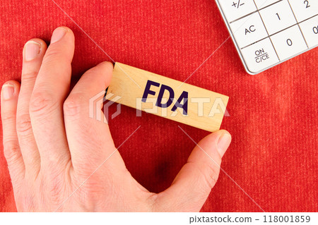 FDA Food and Drug Administration from wooden alphabet cubes made up of blocks with the help of a hand on a red background FDA Food and Drug Administration from wooden alphabet cubes made up of blocks with the help of a hand on a red background 118001859