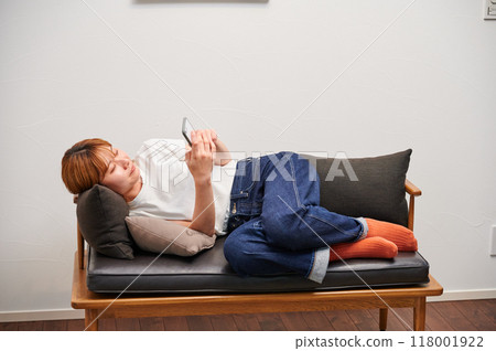 A woman operating a smartphone at home 118001922